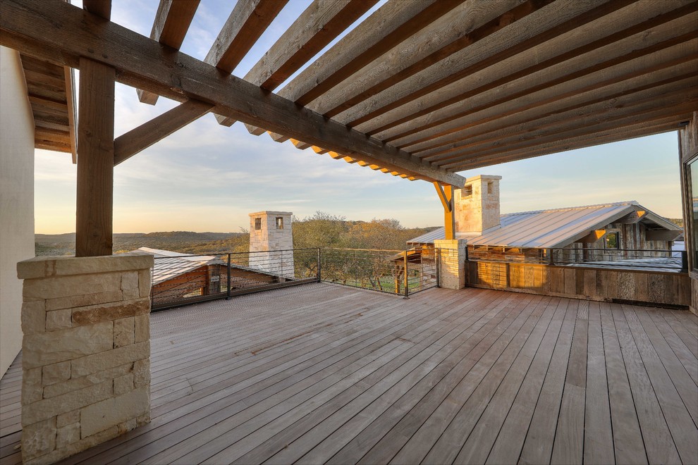 Huge mountain style metal railing balcony photo in Austin with a pergola