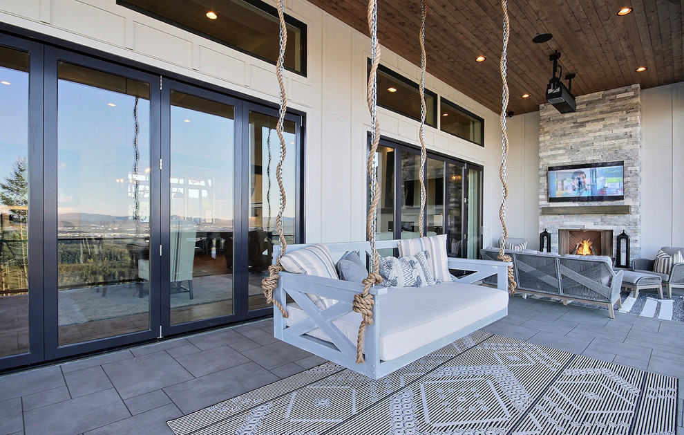 Стильный дизайн: огромный балкон и лоджия в стиле кантри с уличным камином, навесом и стеклянными перилами - последний тренд