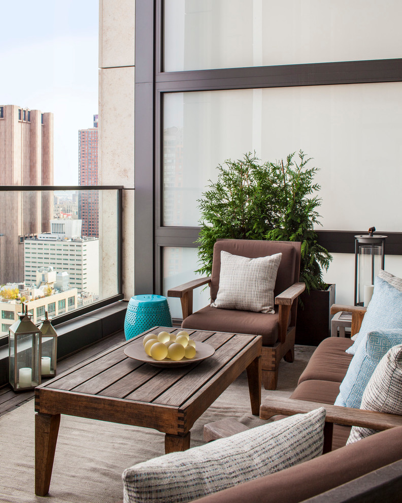 Photo of a medium sized contemporary apartment balcony in New York with a roof extension.
