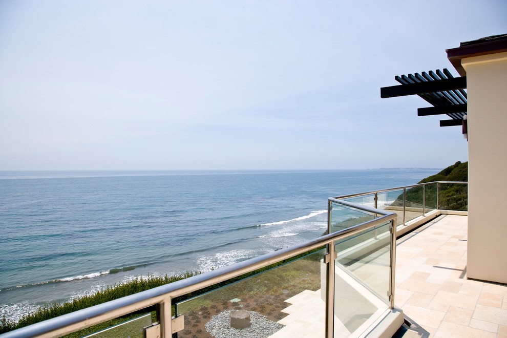 Example of a large island style glass railing balcony design in Santa Barbara with a pergola