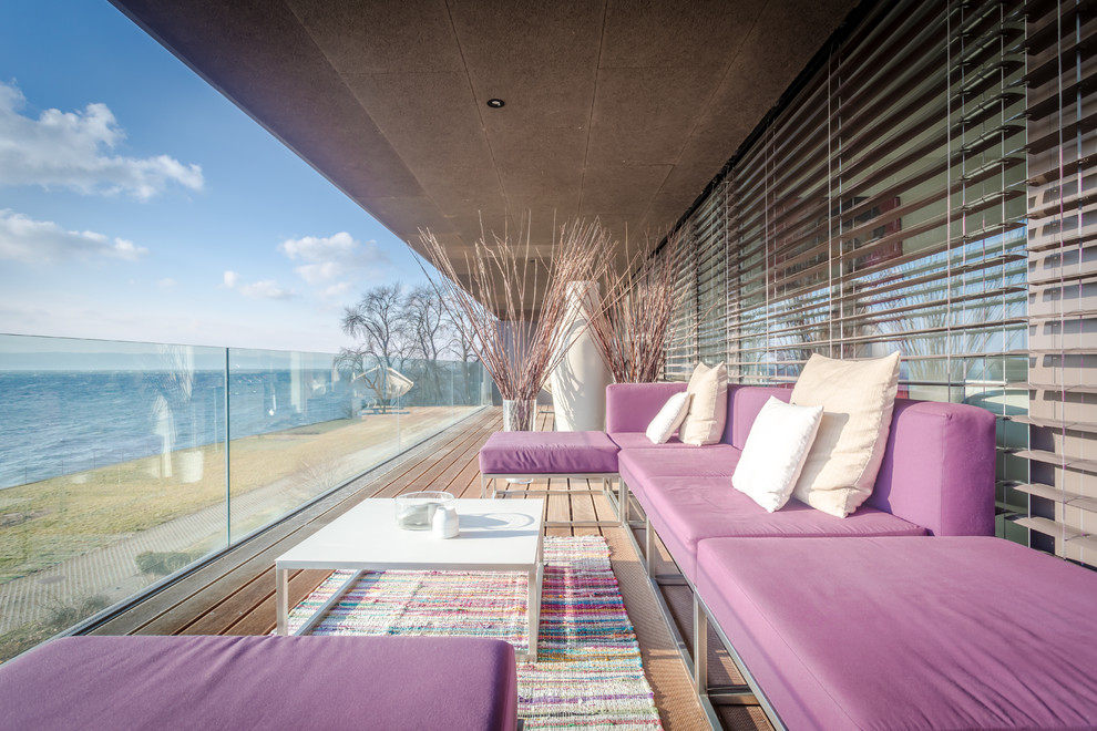 Идея дизайна: балкон и лоджия в современном стиле с растениями в контейнерах, козырьком и стеклянными перилами