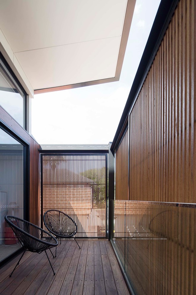 Immagine di un privacy sul balcone design di medie dimensioni con un tetto a sbalzo e parapetto in vetro