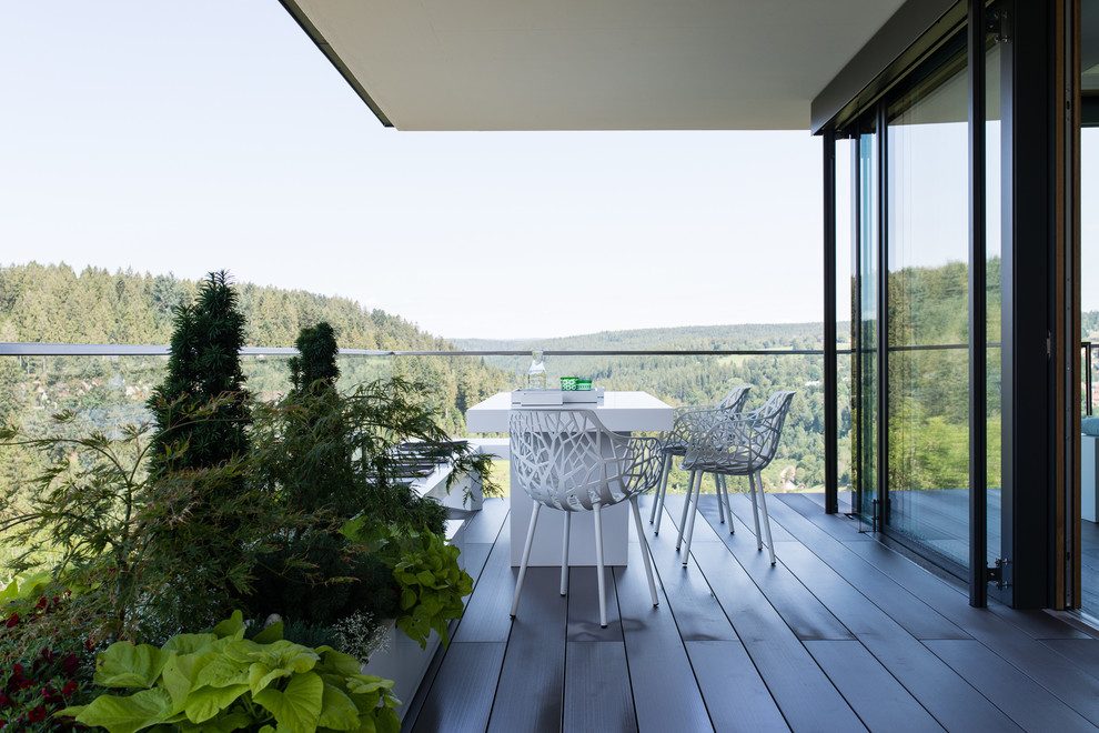 Ispirazione per un balcone moderno di medie dimensioni con un giardino in vaso, un tetto a sbalzo e parapetto in vetro