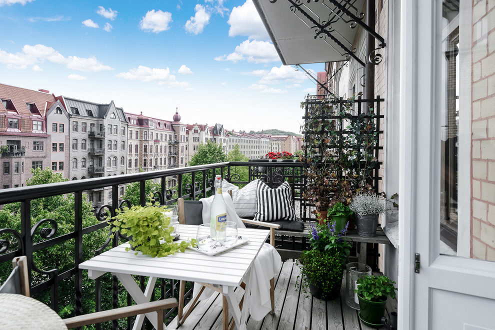 Bild på en mellanstor skandinavisk balkong, med utekrukor, takförlängning och räcke i metall
