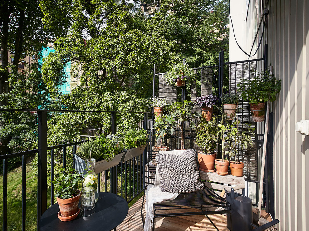 Cette image montre un petit balcon nordique avec des plantes en pot et un garde-corps en métal.