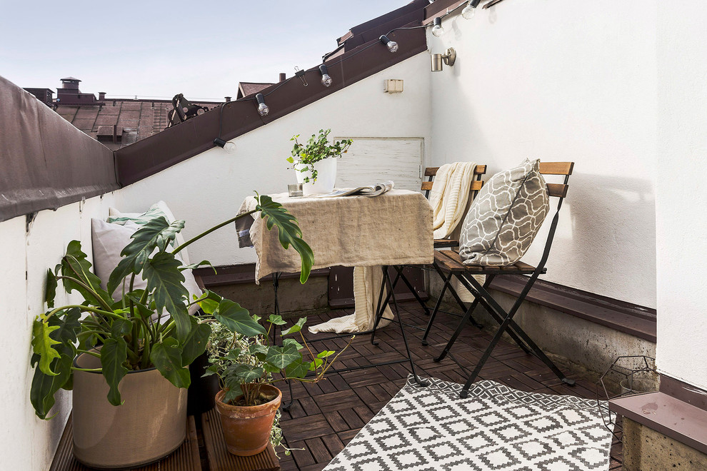 На фото: балкон и лоджия среднего размера в скандинавском стиле с растениями в контейнерах и перилами из смешанных материалов без защиты от солнца с