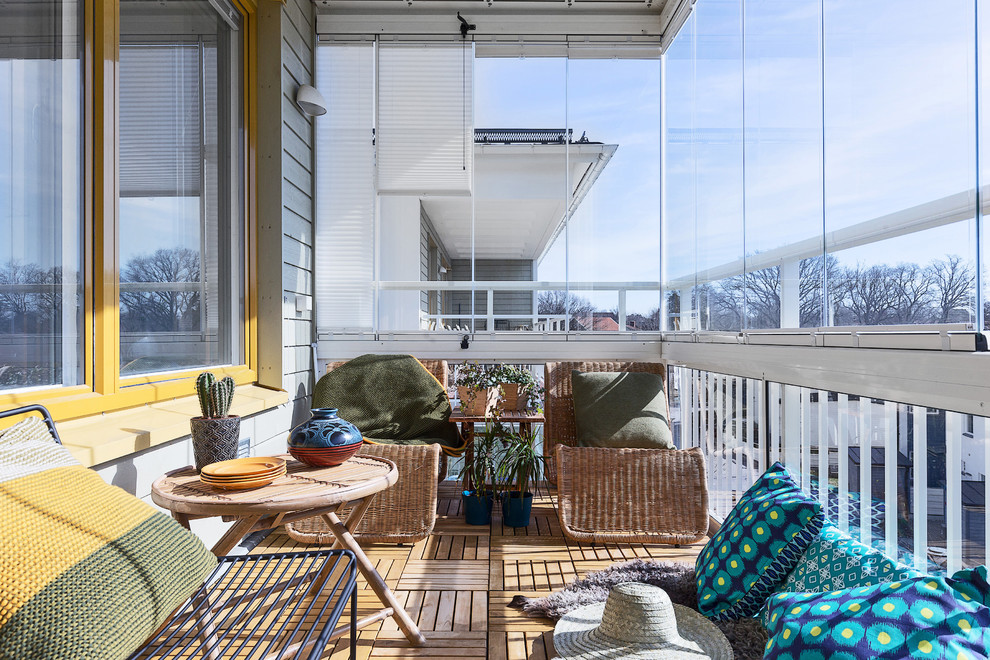 Skandinavisk inredning av en balkong, med takförlängning och räcke i glas