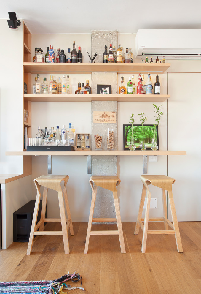Réalisation d'un petit bar de salon linéaire nordique en bois clair avec des tabourets, un placard sans porte, un sol en bois brun et un sol marron.