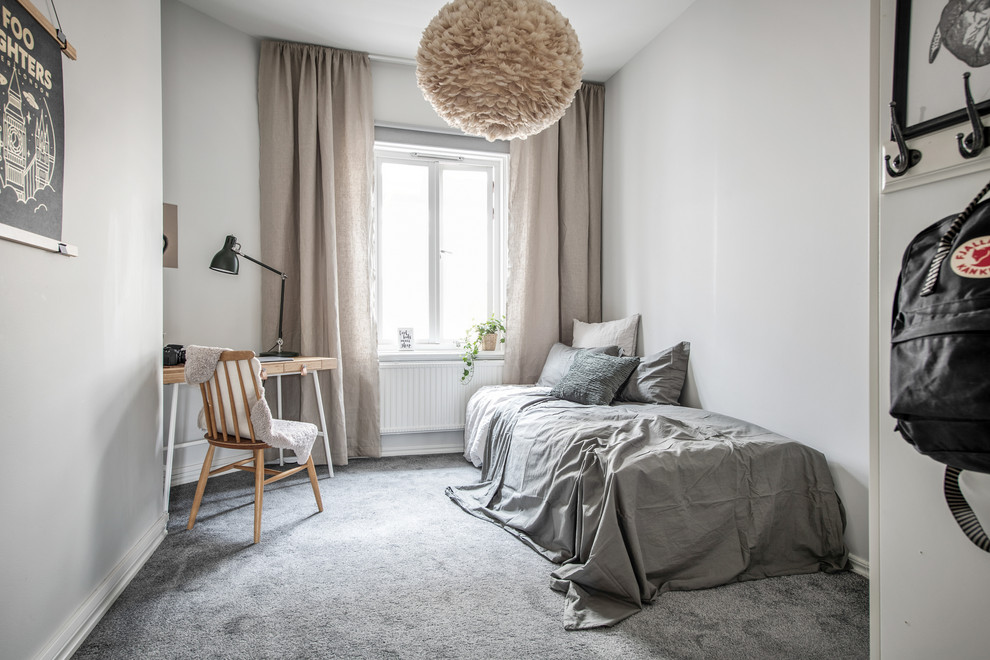 Foto på ett minimalistiskt könsneutralt barnrum kombinerat med sovrum, med vita väggar, heltäckningsmatta och grått golv