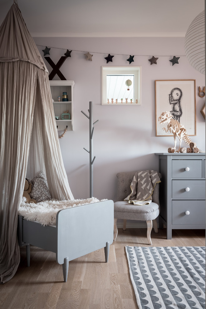 Inspiration for a scandi gender neutral toddler’s room in Gothenburg with grey walls and light hardwood flooring.