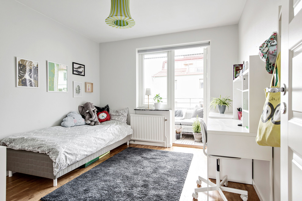 Photo of a scandi gender neutral kids' bedroom in Gothenburg with grey walls, medium hardwood flooring and brown floors.