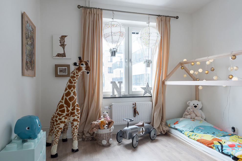 Idéer för ett skandinaviskt könsneutralt småbarnsrum kombinerat med sovrum, med vita väggar och ljust trägolv