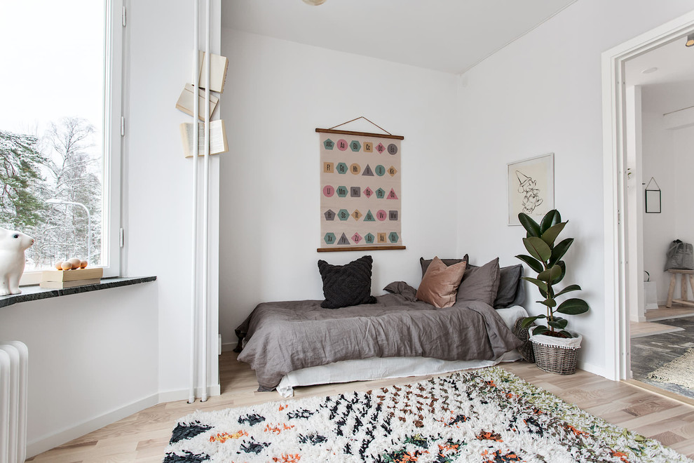 Design ideas for a medium sized scandi gender neutral children’s room in Stockholm with white walls, beige floors and light hardwood flooring.