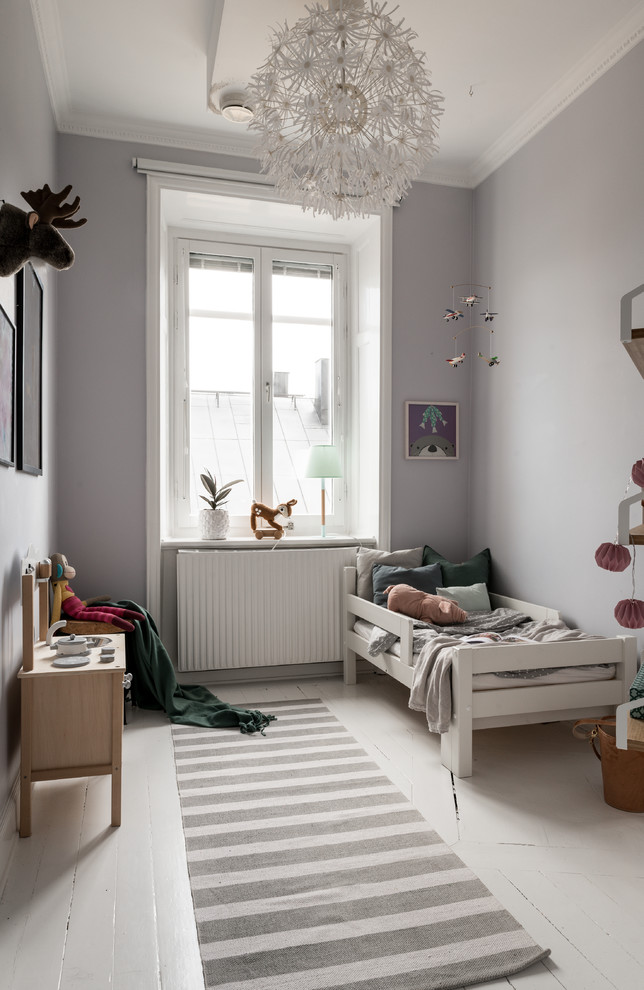 Inredning av ett minimalistiskt könsneutralt småbarnsrum kombinerat med sovrum, med grå väggar, målat trägolv och vitt golv