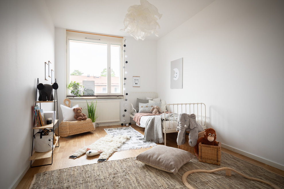 Idée de décoration pour une chambre d'enfant de 1 à 3 ans nordique avec un mur blanc et parquet clair.