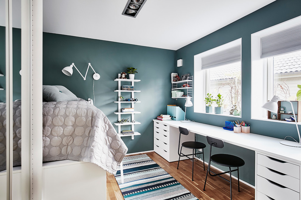 Foto på ett mellanstort minimalistiskt könsneutralt barnrum kombinerat med sovrum och för 4-10-åringar, med mellanmörkt trägolv, blå väggar och brunt golv