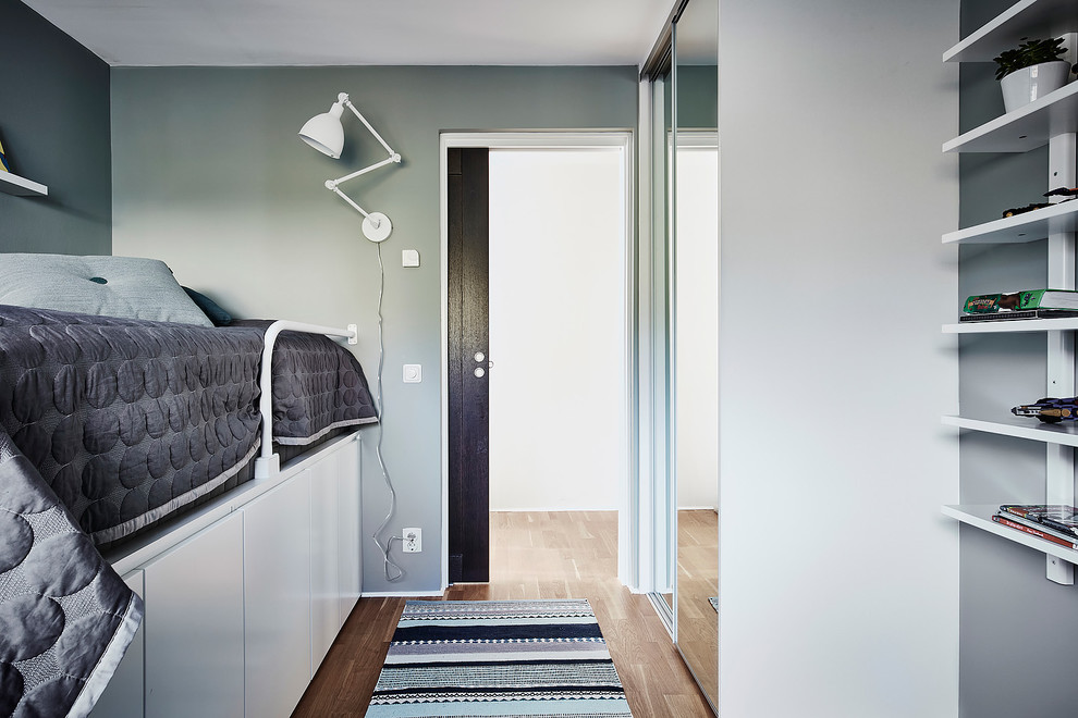Idéer för ett mellanstort minimalistiskt könsneutralt barnrum kombinerat med sovrum och för 4-10-åringar, med blå väggar, mellanmörkt trägolv och brunt golv