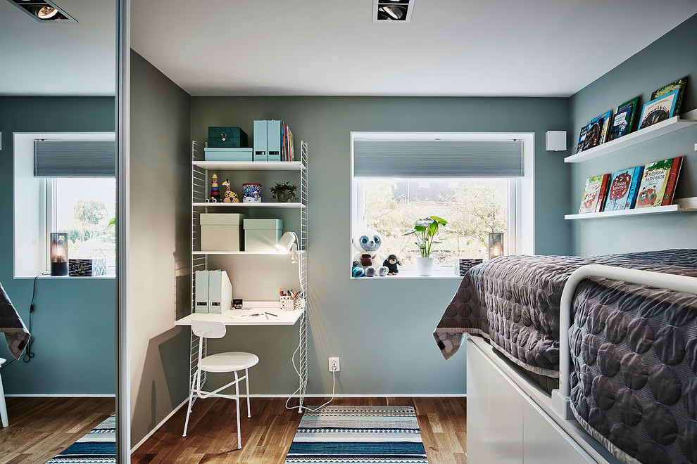 Ispirazione per una cameretta per bambini da 4 a 10 anni scandinava di medie dimensioni con pareti blu, pavimento in legno massello medio e pavimento marrone