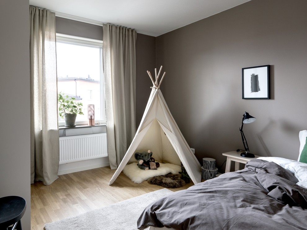 Design ideas for a medium sized modern gender neutral children’s room in Stockholm with beige walls, light hardwood flooring and brown floors.