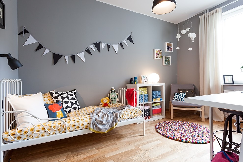 На фото: нейтральная детская среднего размера в скандинавском стиле с спальным местом, серыми стенами, светлым паркетным полом и коричневым полом для ребенка от 4 до 10 лет