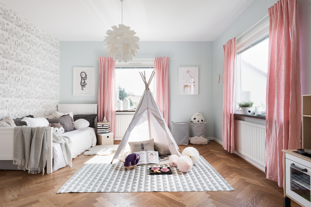 This is an example of a large scandi gender neutral children’s room in Gothenburg with medium hardwood flooring and multi-coloured walls.