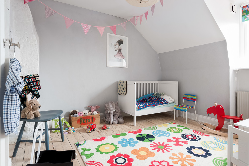 Exempel på ett mellanstort minimalistiskt barnrum kombinerat med lekrum, med grå väggar, ljust trägolv och beiget golv