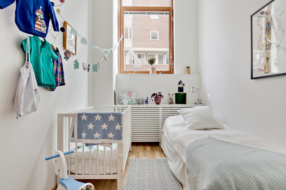 На фото: нейтральная детская среднего размера в скандинавском стиле с спальным местом, белыми стенами и светлым паркетным полом для ребенка от 1 до 3 лет