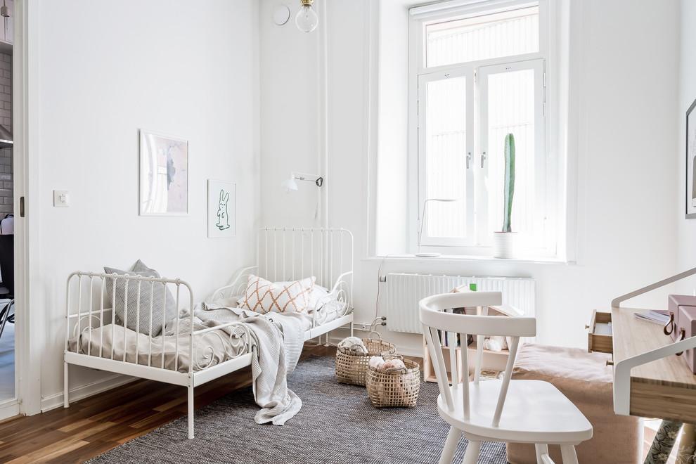 Imagen de dormitorio infantil de 4 a 10 años nórdico con paredes blancas, suelo de madera en tonos medios y suelo marrón
