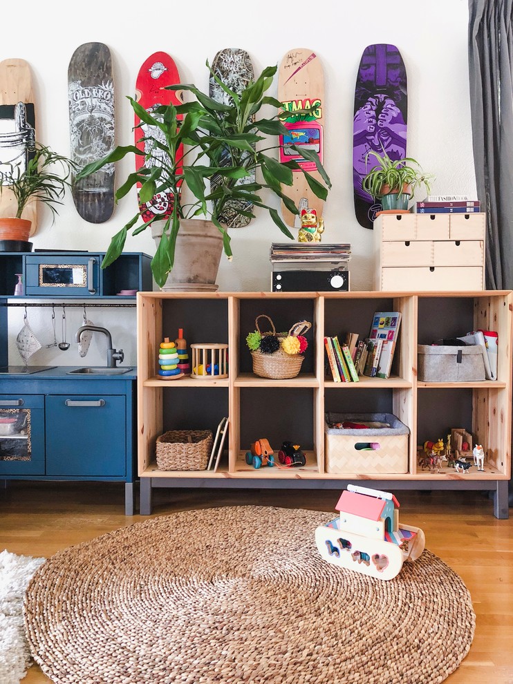 Inspiration för eklektiska könsneutrala småbarnsrum kombinerat med lekrum, med vita väggar, mellanmörkt trägolv och beiget golv