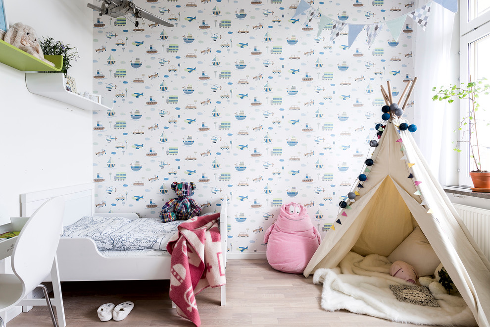 Nordisk inredning av ett mellanstort könsneutralt barnrum kombinerat med sovrum och för 4-10-åringar, med flerfärgade väggar och ljust trägolv
