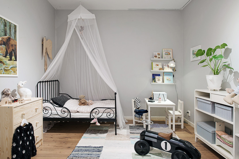 На фото: нейтральная детская среднего размера в скандинавском стиле с серыми стенами, светлым паркетным полом и спальным местом для ребенка от 1 до 3 лет с