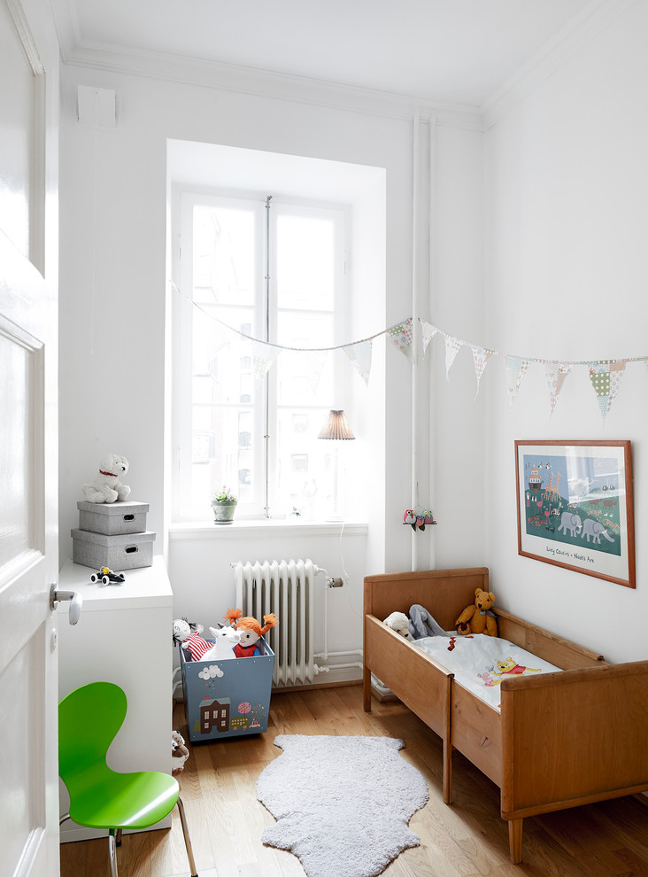 Design ideas for a medium sized scandinavian gender neutral toddler’s room in Gothenburg with white walls and medium hardwood flooring.