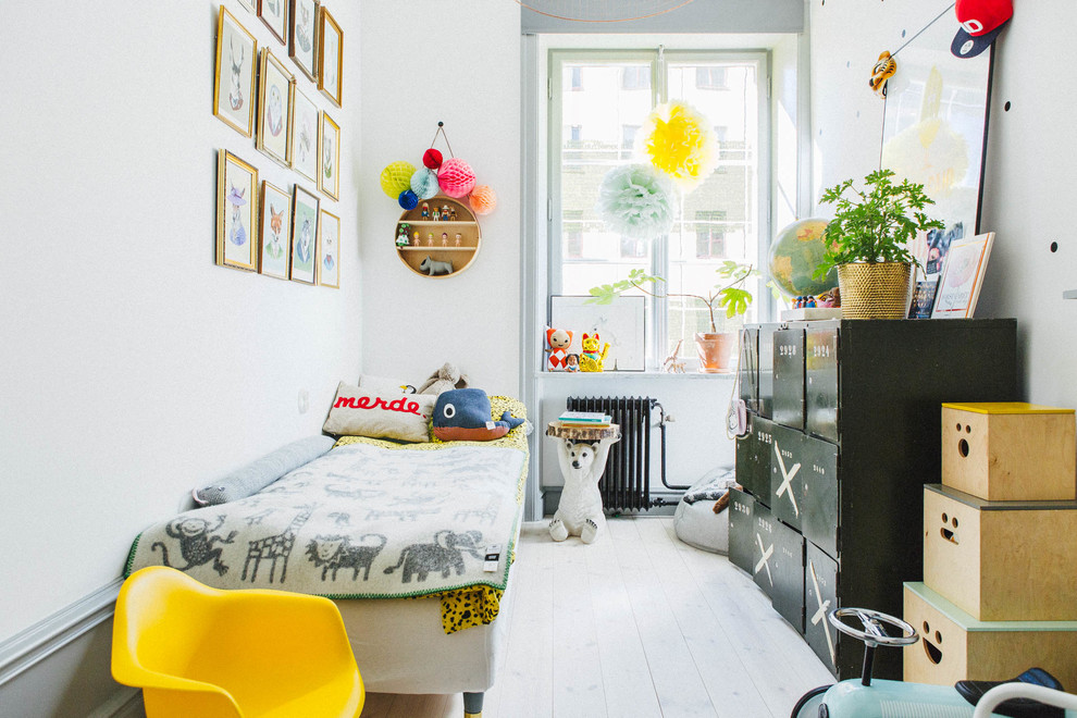 Photo of a medium sized scandi gender neutral children’s room in Stockholm with white walls and light hardwood flooring.