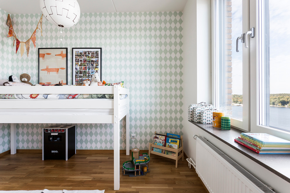 Bild på ett mellanstort skandinaviskt barnrum kombinerat med sovrum, med flerfärgade väggar och ljust trägolv