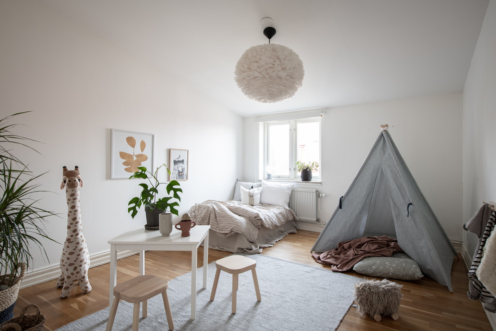На фото: детская в скандинавском стиле с спальным местом, белыми стенами и светлым паркетным полом для ребенка от 4 до 10 лет, девочки
