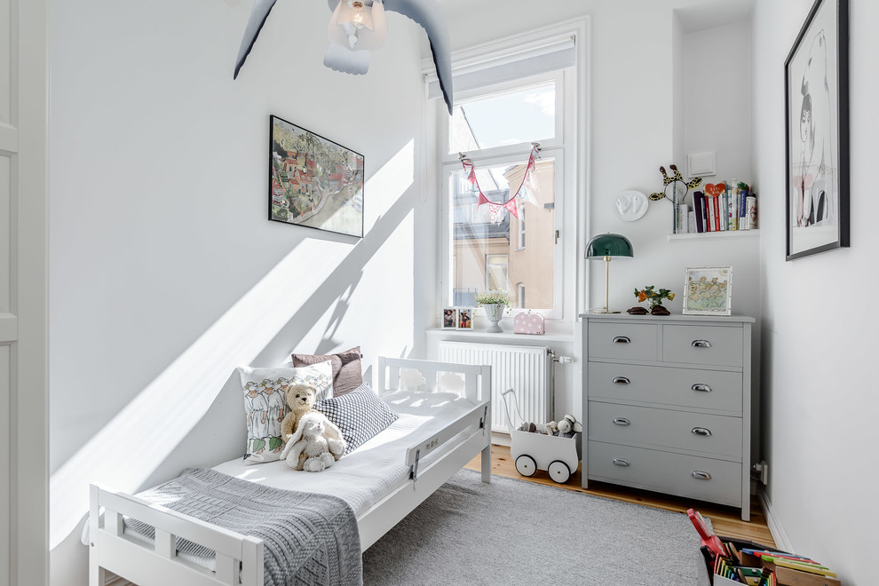 Réalisation d'une petite chambre d'enfant de 1 à 3 ans nordique avec un mur blanc et parquet clair.