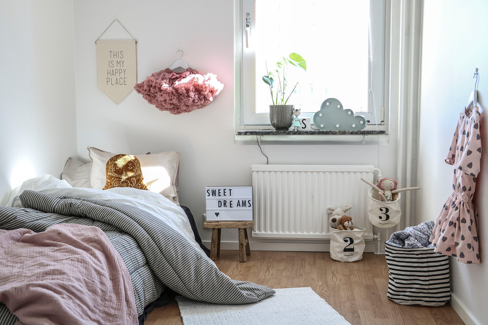 Minimalistisk inredning av ett flickrum kombinerat med sovrum och för 4-10-åringar, med vita väggar och mellanmörkt trägolv