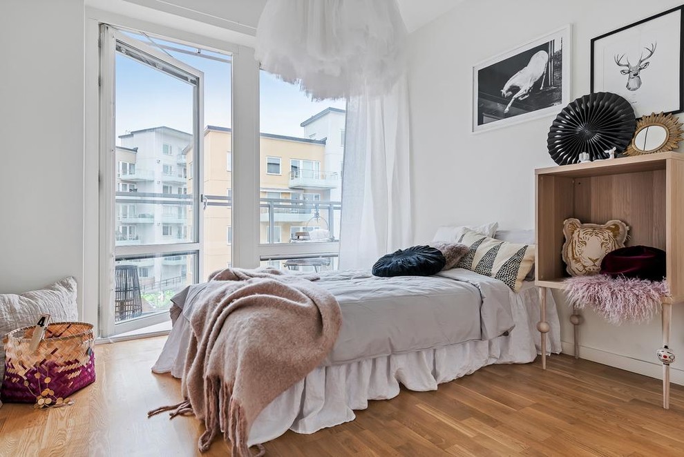Medium sized scandi children’s room for girls in Stockholm with white walls and medium hardwood flooring.