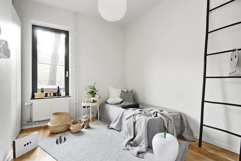 Idéer för att renovera ett nordiskt könsneutralt småbarnsrum kombinerat med sovrum, med vita väggar, mellanmörkt trägolv och brunt golv