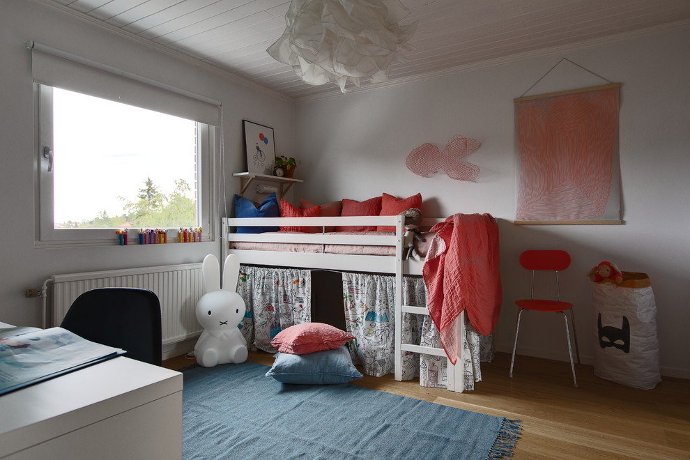 На фото: детская в скандинавском стиле с белыми стенами, паркетным полом среднего тона и коричневым полом для ребенка от 4 до 10 лет, девочки