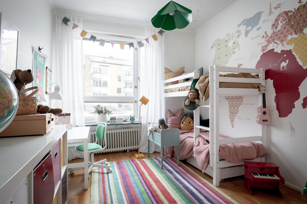 Immagine di una cameretta da bambina da 4 a 10 anni nordica con pareti bianche, pavimento in legno massello medio e pavimento marrone