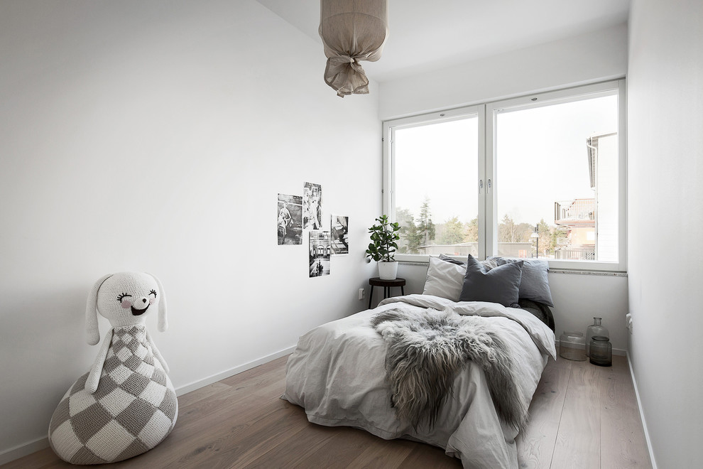 Ejemplo de dormitorio infantil escandinavo de tamaño medio con paredes blancas y suelo de madera clara