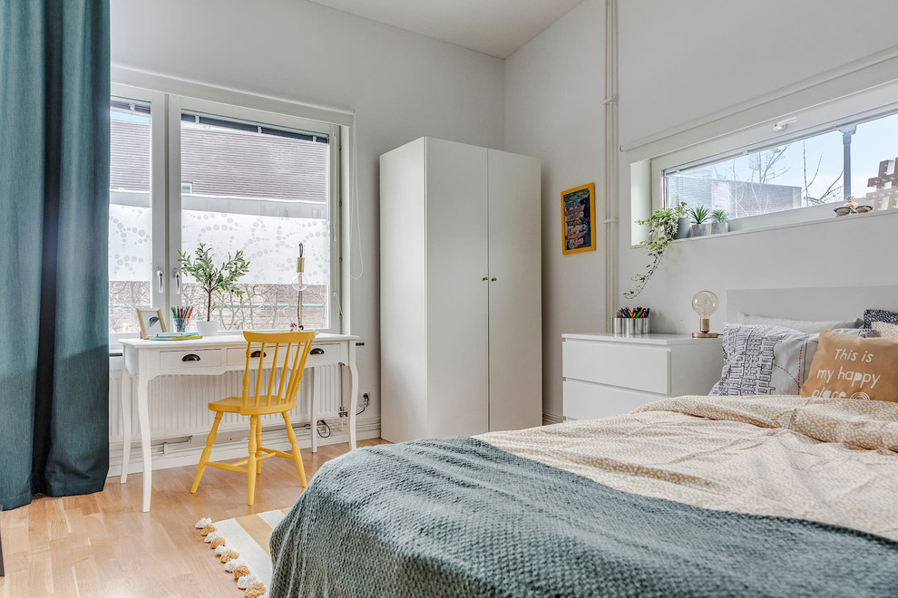 Inredning av ett minimalistiskt barnrum kombinerat med sovrum, med vita väggar, ljust trägolv och beiget golv