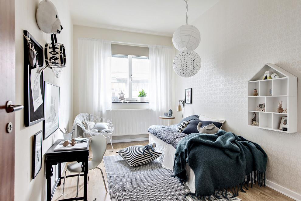 Ejemplo de dormitorio infantil escandinavo de tamaño medio con paredes blancas, suelo de madera clara y suelo marrón