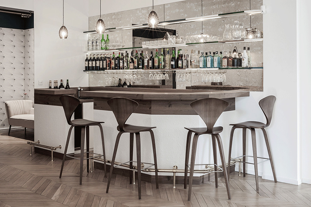 Esempio di un grande bancone bar design con top in legno, paraspruzzi a specchio e parquet chiaro