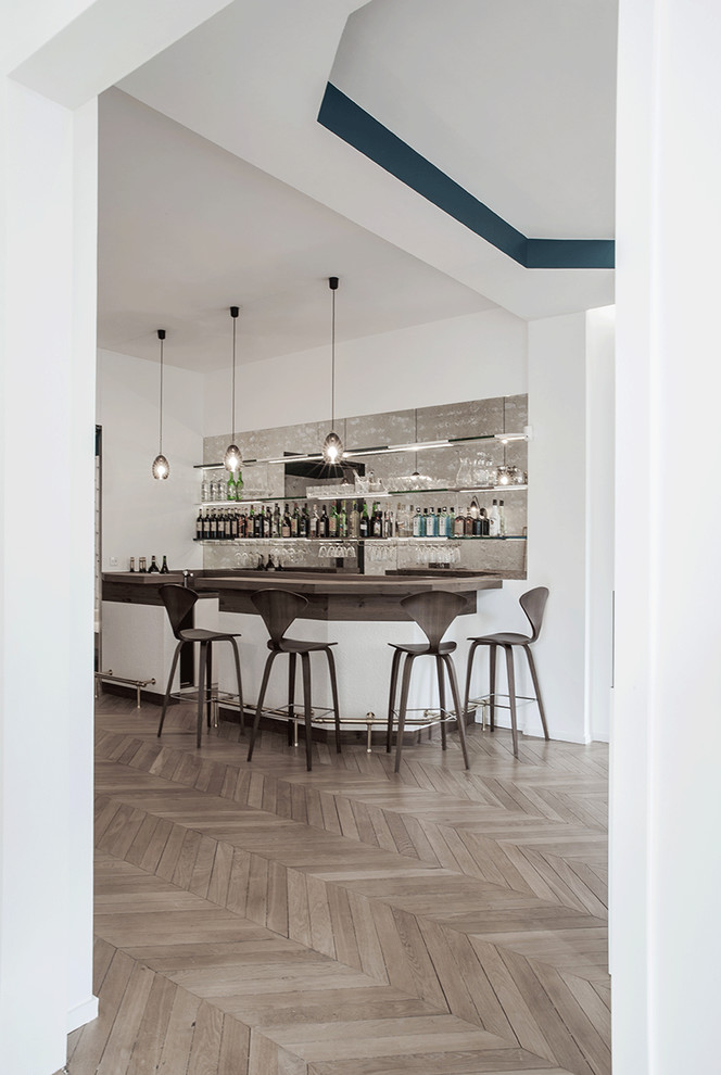 Große Moderne Hausbar in U-Form mit Bartheke, Arbeitsplatte aus Holz, Rückwand aus Spiegelfliesen und hellem Holzboden in Paris