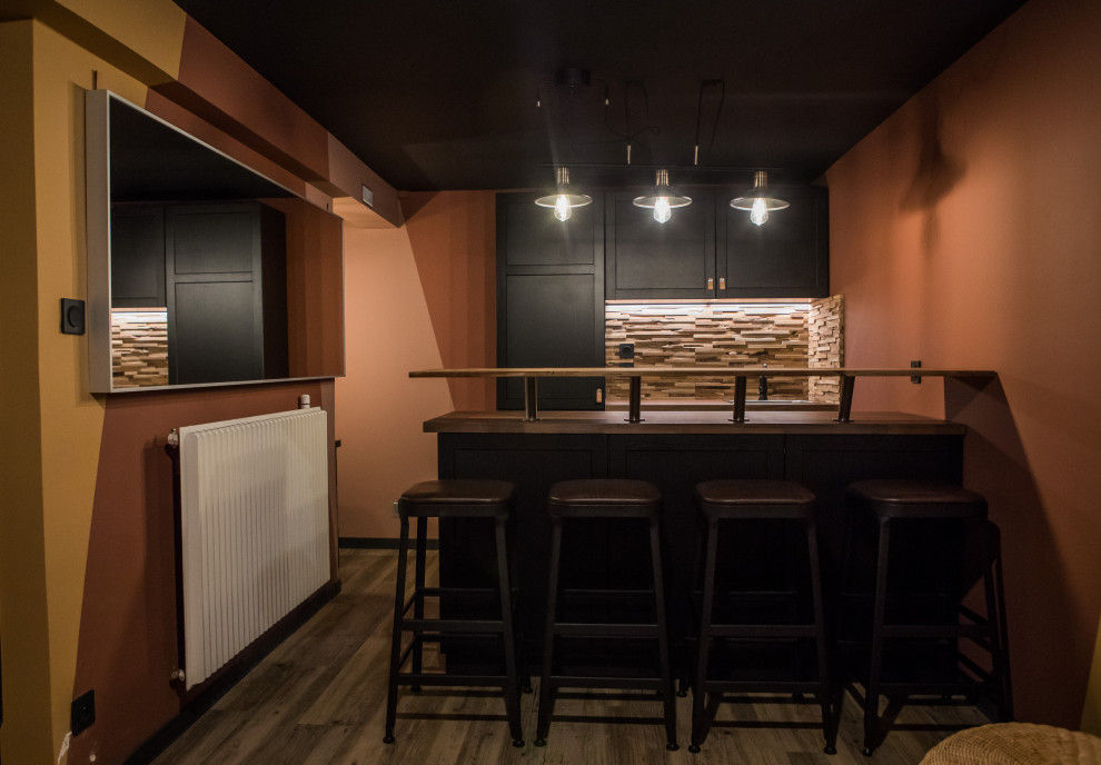 Réalisation d'un bar de salon parallèle craftsman avec des tabourets, un évier posé, un placard à porte affleurante, des portes de placard noires, un plan de travail en bois, une crédence en bois et parquet en bambou.