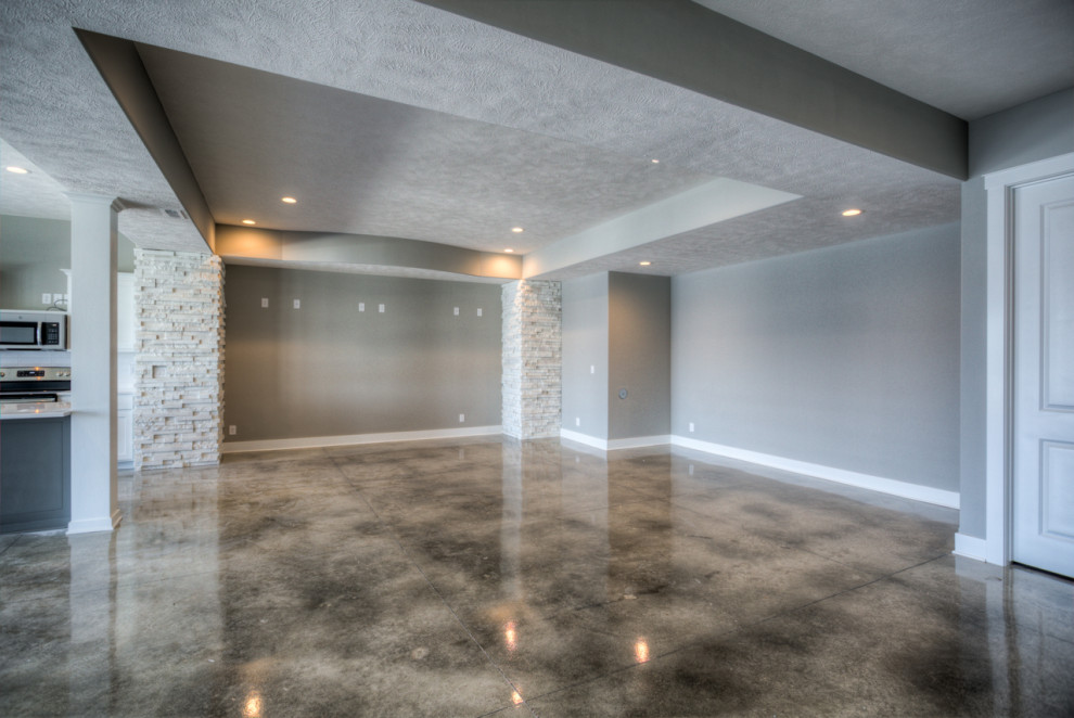 Cette image montre un grand sous-sol minimaliste donnant sur l'extérieur avec sol en béton ciré.
