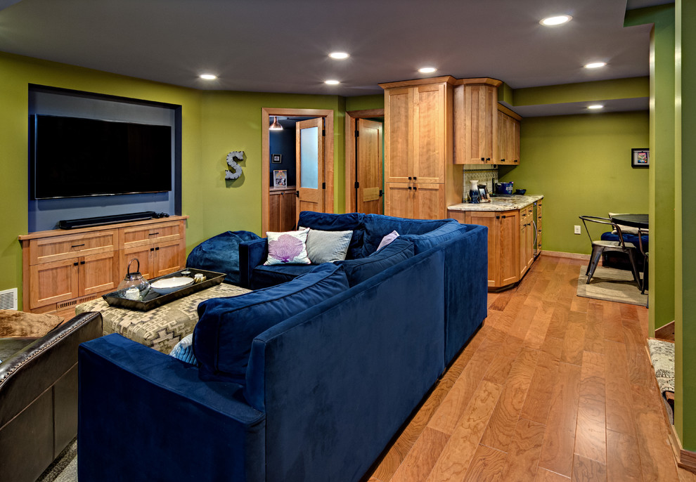 Foto de sótano con ventanas de estilo americano grande sin chimenea con paredes verdes, suelo de madera en tonos medios y suelo marrón