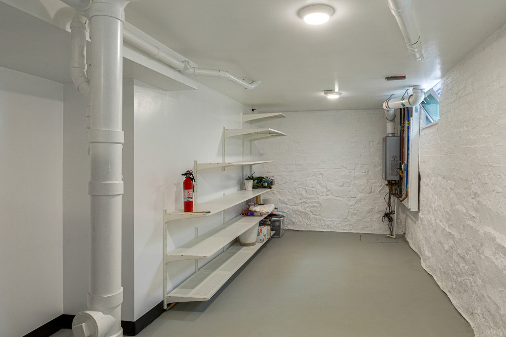Immagine di una piccola taverna moderna seminterrata con pareti bianche, pavimento in cemento e pavimento grigio